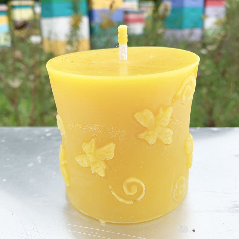 Circular beeswax candle with bee pattern