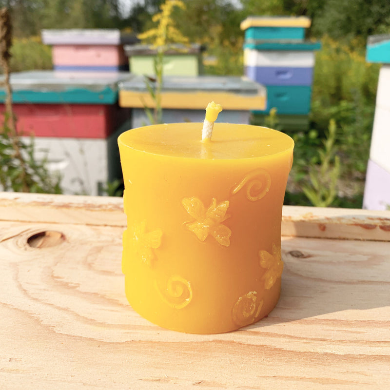 Circular beeswax candle with bee pattern